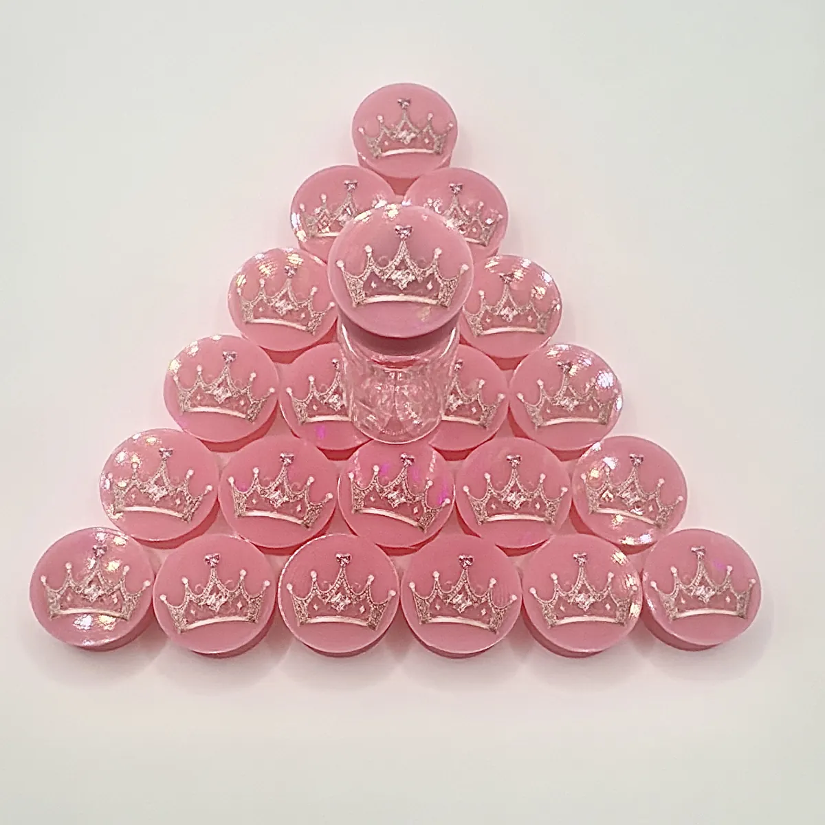 Pink vial caps printed with a crown logo, stacked in a pyramid